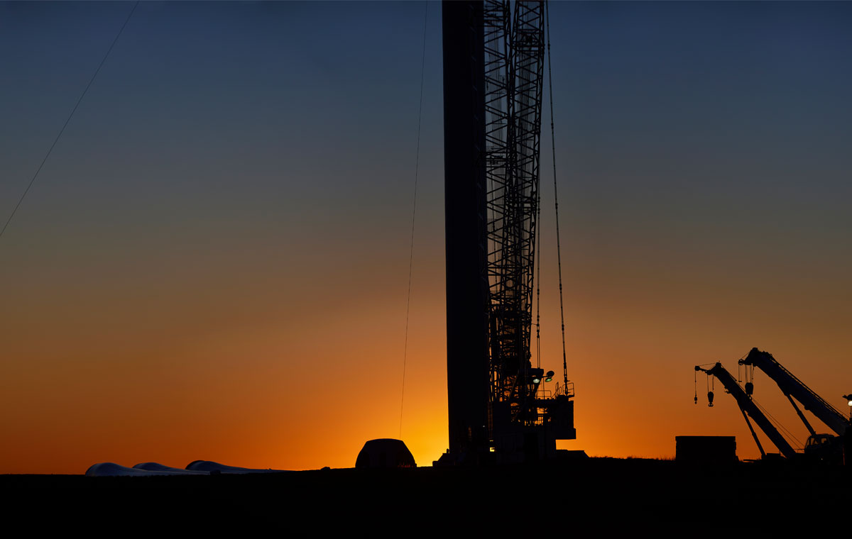 Wind turbine construction cranes silhouetted at sunset