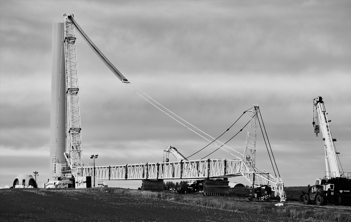 Cranes assembling wind turbine components in a field