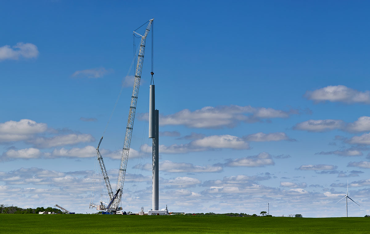 Crane installing a wind turbine tower in a rural landscape